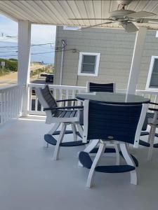 Un patio con una mesa y sillas en un porche. en Welcome To Your Dream Vacation Rental In The Heart Of Peahala Park, Just Steps Away From The Pristine Beaches Of The Ocean Block, en Peahala Park