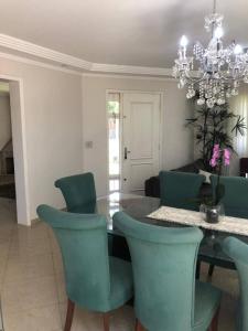 ein Esszimmer mit einem Glastisch und grünen Stühlen in der Unterkunft Crisálidas experience in Foz do Iguaçu