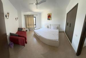 ein Schlafzimmer mit einem weißen Bett und einem roten Sofa in der Unterkunft Swanlake Lagoon Luxury Villa in Zāwiyat al ‘Awwāmah + 10 Fotos
