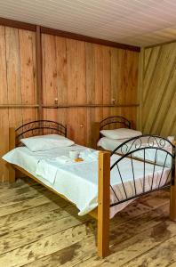a bed in a room with wooden walls at Flor da Mata in Iranduba