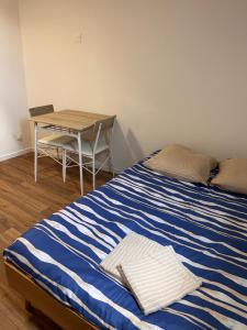 a bed with a blue and white striped sheets and a table at Studio urbain et fonctionnel in Périgueux