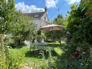 a table and chairs with an umbrella in a yard at Maison de Famille avec Jardin - Coeur du village - Zoo de Beauval in Saint-Aignan