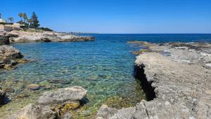 a large body of water with rocks and the ocean at B&B Villa Pegaso in Fontane Bianche
