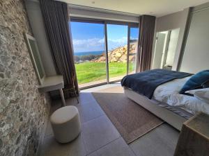 a bedroom with a bed and a large window at Casa de Santos - Aloe Villa in Mossel Bay