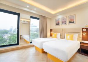 a hotel room with two beds and a large window at Bloom Boutique l Sector 45 Gurugram in Gurgaon