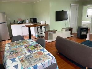 ein Wohnzimmer mit Tisch und Stühlen und einem Fernseher in der Unterkunft Cabaña El Retiro in Lebu