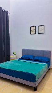 a bedroom with a bed with a blue bedspread at Arrafah Homestay Klebang in Tranquerah