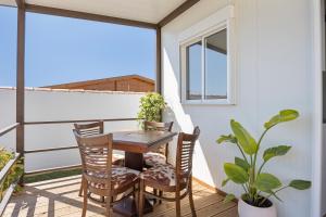einen Balkon mit einem Holztisch und Stühlen sowie einem Fenster in der Unterkunft Casa Con Jardín y piscina in Chiclana de la Frontera