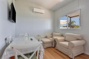 ein weißes Wohnzimmer mit einem Tisch und zwei Stühlen in der Unterkunft Casa Con Jardín y piscina in Chiclana de la Frontera