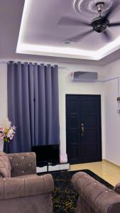a living room with a couch and a blue curtain at Arrafah Homestay Klebang in Tranquerah