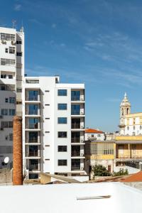 a white apartment building with a clock tower in the background at The View at The Downtown Faro in Faro