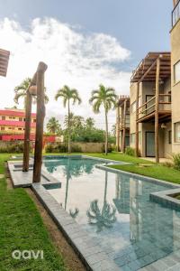 a swimming pool in front of a building with palm trees at Qavi - Casa com Piscina Privativa - Lambari 07 in Barra do Camaragibe