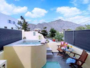 a hot tub on a balcony with a table and chairs at Marina's Studios in Perivolos