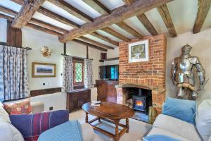 a living room with a brick fireplace and a table at Finest Retreats - Sandhill Cottage with hot tub in Turners Hill