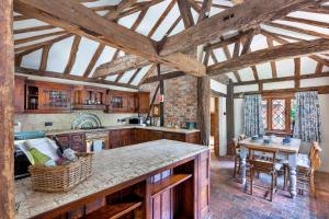 a large kitchen with wooden ceilings and a table at Finest Retreats - Sandhill Cottage with hot tub in Turners Hill