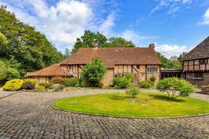a large brick house with a garden in front of it at Finest Retreats - Sandhill Cottage with hot tub in Turners Hill