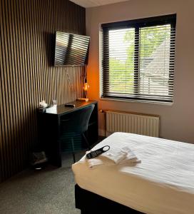 a hotel room with a bed and a desk and a window at Hotel restaurant De Roode Leeuw in Terborg +66 photos