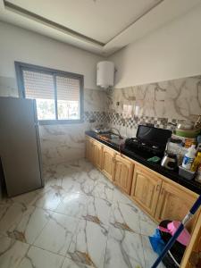 a kitchen with a stove and a refrigerator at Houssam immobilier 7 in Souira Guedima