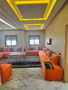 a living room with orange couches and a table at Houssam immobilier 7 in Souira Guedima +5 photos