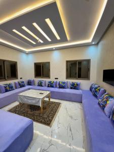 a living room with purple couches and a table at Houssam immobilier 7 in Souira Guedima