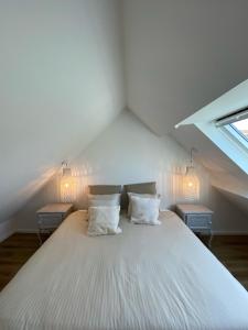 a bedroom with a large white bed with two lamps at L'Opale des Tribus in Audresselles +49 photos