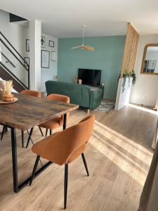 a living room with a table and chairs and a green couch at La longère Cosy & Centrale in Bétheny