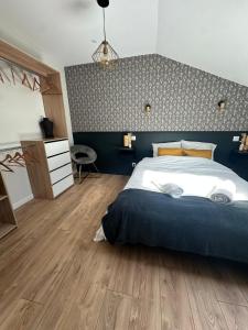 a bedroom with a large bed with a blue wall at La longère Cosy & Centrale in Bétheny