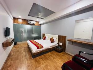 a bedroom with a bed and a tv and a chair at the valentine hotel in Surat