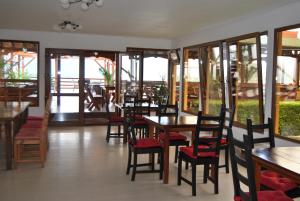 a restaurant with wooden tables and chairs and windows at Pension La Ponton in Eşelniţa