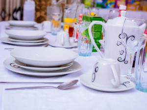 a white table with plates and cups and a spoon at Fanham Homes in Bulawayo