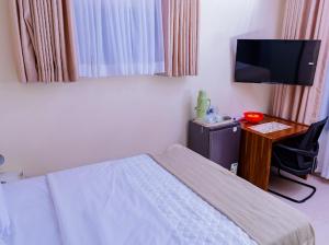 a bedroom with a bed and a desk with a television at Fanham Homes in Bulawayo