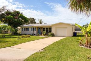 a white house with a garage and palm trees at Walk to Jetty Park Harbor District Home! in Fort Pierce