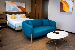 a blue couch and a bed in a hotel room at Golden Tulip Kin-Oasis Kinshasa in Kinshasa