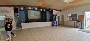 a woman walking in a room with a large screen at MOBIL HOME in Ivry-la-Bataille