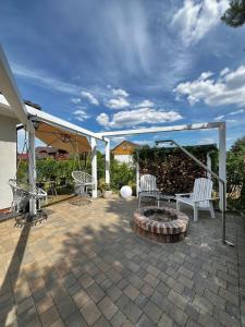 a patio with two white chairs and a fire pit at Sosenkowe Apartamenty Balia & Jacuzzi in Kuźnica Głogowska +33 photos