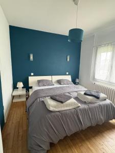 a bedroom with a large bed with a blue wall at Charmante maison in Dinard