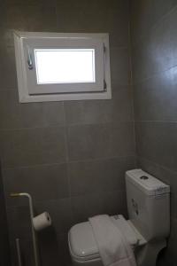 a small bathroom with a toilet and a window at Omega Suites By Platform 357 in Ayios Dhometios
