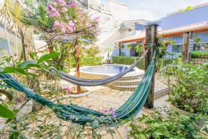 a hammock in front of a house with a pool at Velinn Pousada Remanso do Mar in Ubatuba