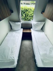 two beds in a small room with a window at Mobilheim 90 in Hüde +2 photos