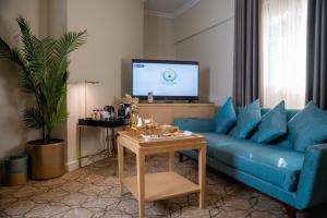 a living room with a blue couch and a tv at SAJA By Warwick Madinah Hotel in Medina