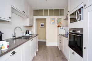 a kitchen with white cabinets and a black appliance at Ocean View Apartment in Filey