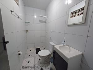 a white bathroom with a toilet and a sink at Casa no centro de Japaratinga in Japaratinga