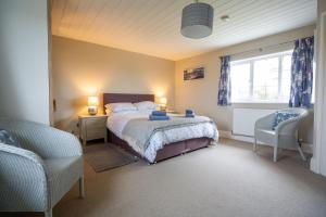 a bedroom with a bed and a chair and a window at Penrose Cottage in Bude