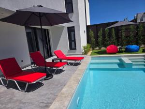 a pool with chairs and umbrellas next to a house at villa Amethyst, private pool with heating and salt water in Lozenets