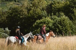 a man and a woman riding horses in a field at Noclegi w domku Koniarza in Porąbka