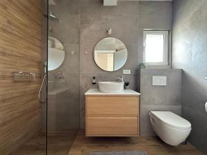 un bagno con lavandino, WC e specchio di Beachfront house Miamore - 10 m from the sea a Mrljane Altre 27 foto