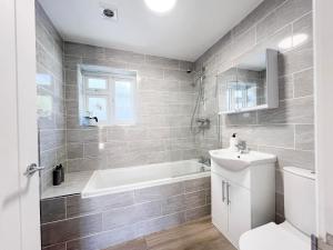 a bathroom with a tub and a toilet and a sink at Hedgehog Cottage in Bury Saint Edmunds +28 photos