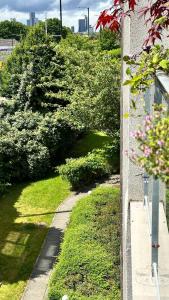 a garden with green grass and bushes next to a wall at Spacious, smart apartment near City Centre and Coop Arena Free parking in Manchester