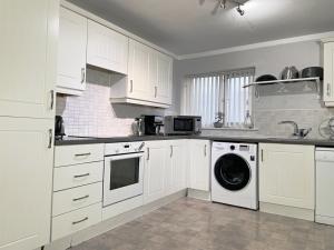 a kitchen with white cabinets and a washing machine at Spacious, smart apartment near City Centre and Coop Arena Free parking in Manchester +13 photos