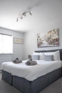 a bedroom with a large bed with white sheets and pillows at Hedgehog Cottage in Bury Saint Edmunds